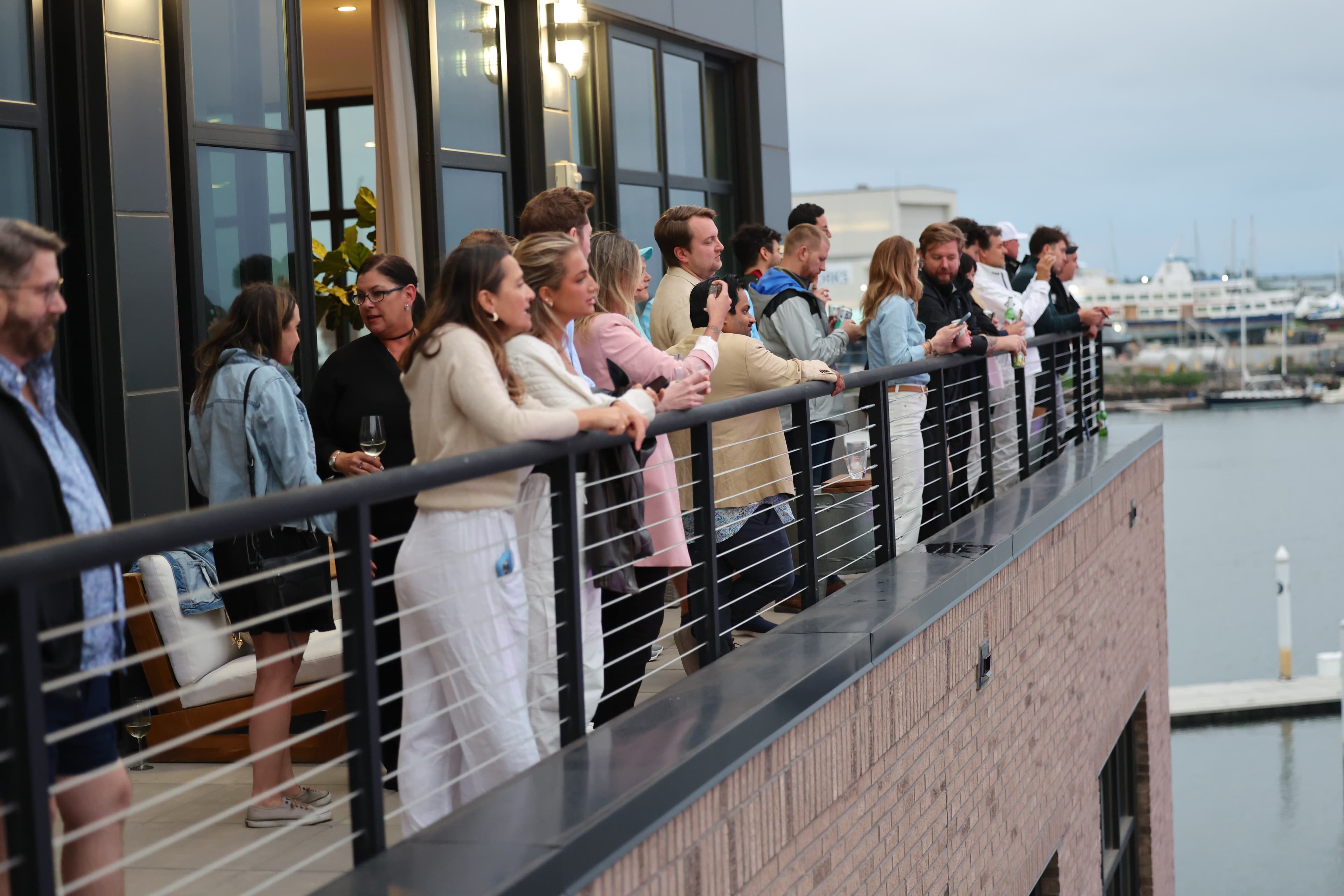 Members on a balcony over the marina at dusk